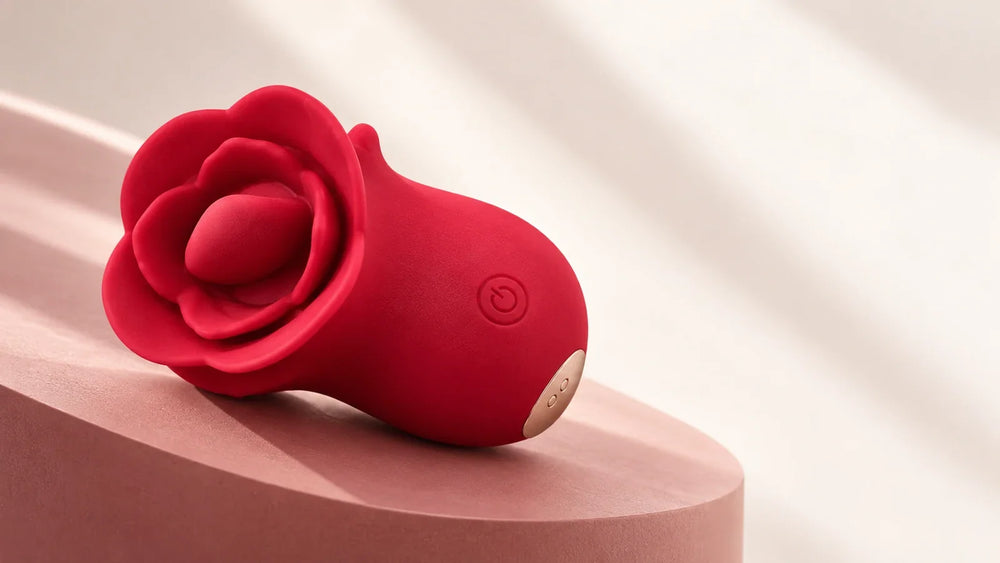 Red Roselle Kiss with a tongue-style head, front button and magnetic charging contacts on a blush display surface.