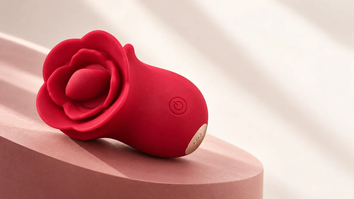 Red Roselle Kiss with a tongue-style head, front button and magnetic charging contacts on a blush display surface.