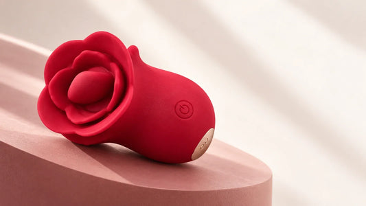 Red Roselle Kiss with a tongue-style head, front button and magnetic charging contacts on a blush display surface.