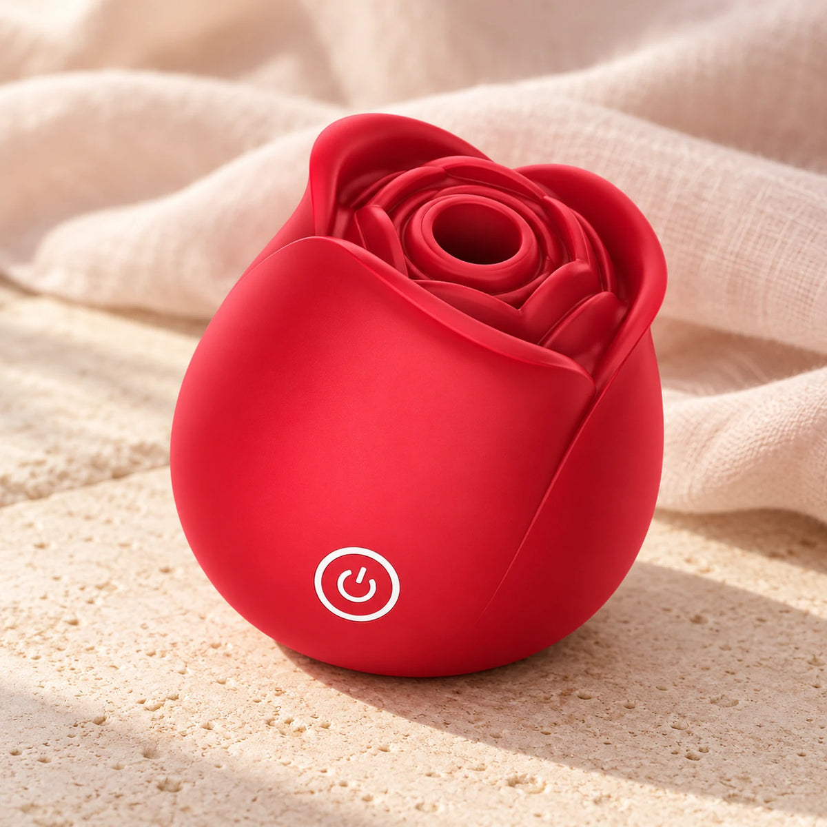 Red Roselle Sync rose-shaped toy on warm stone beside pale linen